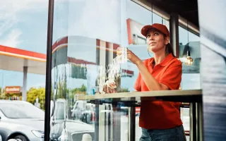 Woman enjoying a coffee and snacks inside a Circle K café, while looking out of a large window